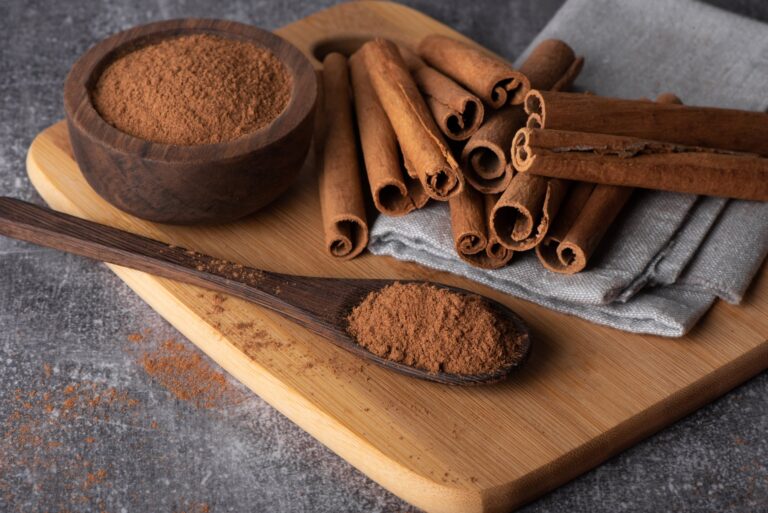 Rama de canela y canela en polvo sobre una superficie, elementos para rituales de prosperidad.